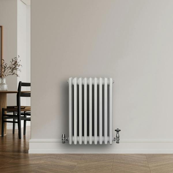 Traditional white 4 column radiator with smooth, glossy finish and chrome valves, mounted on a light-colored wall in a modern interior