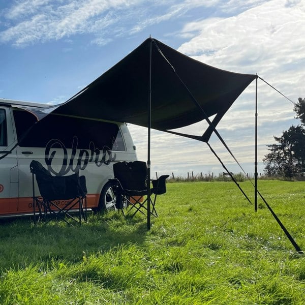 The OLPRO Modern Shade Canopy attached to a campervan with camping chairs.