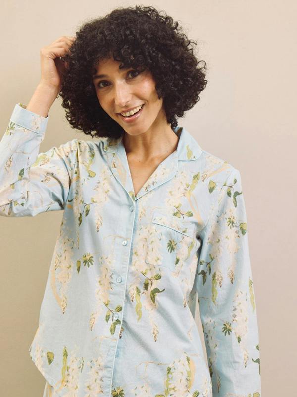 Woman wearing a light blue floral pyjama shirt against a beige background