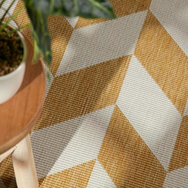 Close-up of a textured surface with geometric pattern and a plant in the corner.