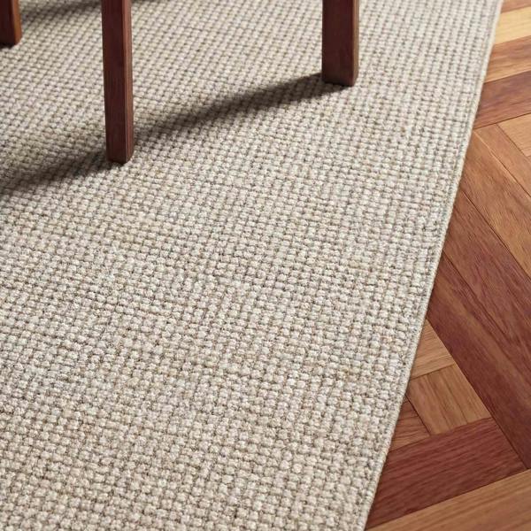 Textured beige rug on a wooden floor
