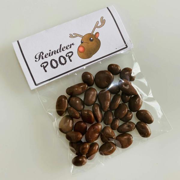 A clear bag filled with chocolate-covered treats topped with a paper label reading Reindeer Poop with a cartoon Rudolph.