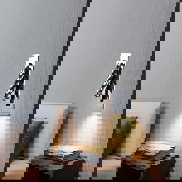 Polished chrome recessed LED reading wall lamp mounted next to a bed over a bedside table 