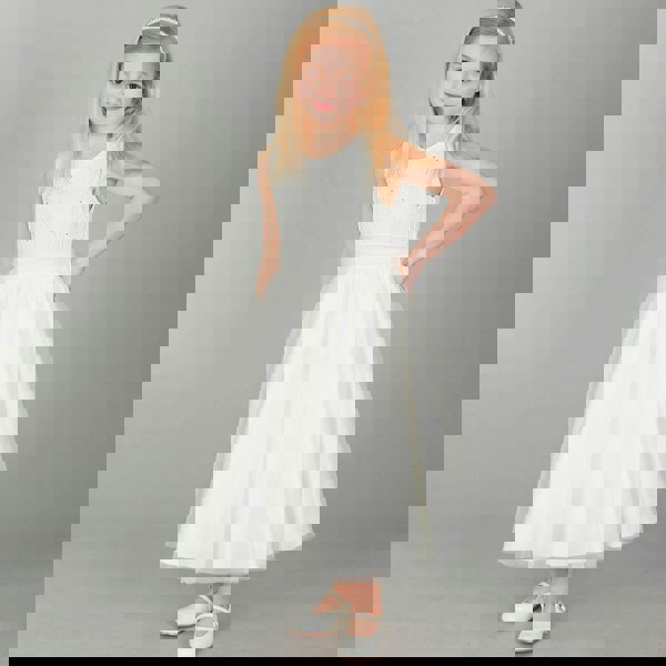 Blonde girl wearing ivory coloured party dress  and whit party shoes