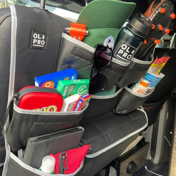 The OLPRO Rear Double Seat Storage Organiser in Grey that is full of summer themed items and attached to the back of the front seats of a camper van.