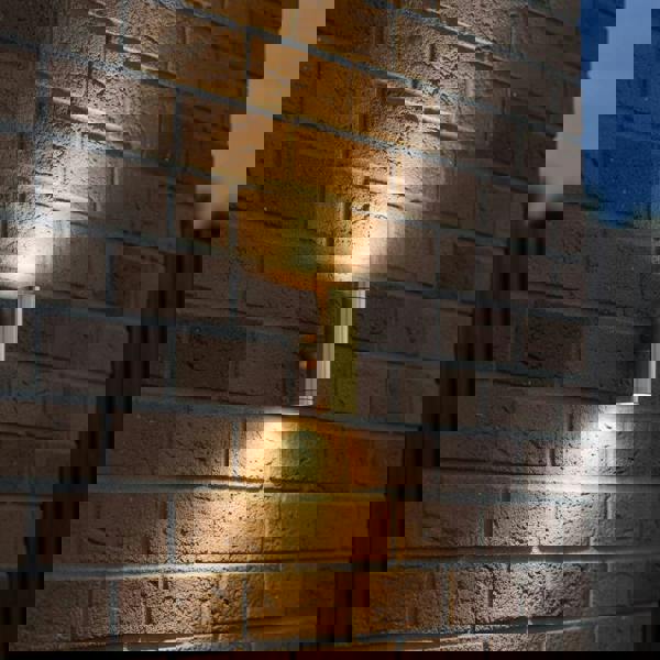 brass up down outdoor wall light mounted on a brick wall of a home 