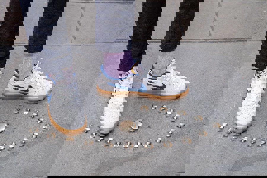 White sneakers with blue accents on a concrete surface with small round objects.