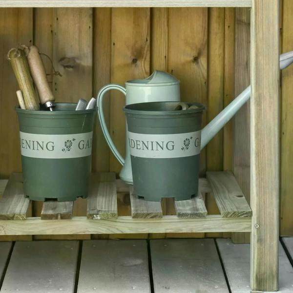 Raised wooden planter box with legs and storage shelf featuring watering cans and pots