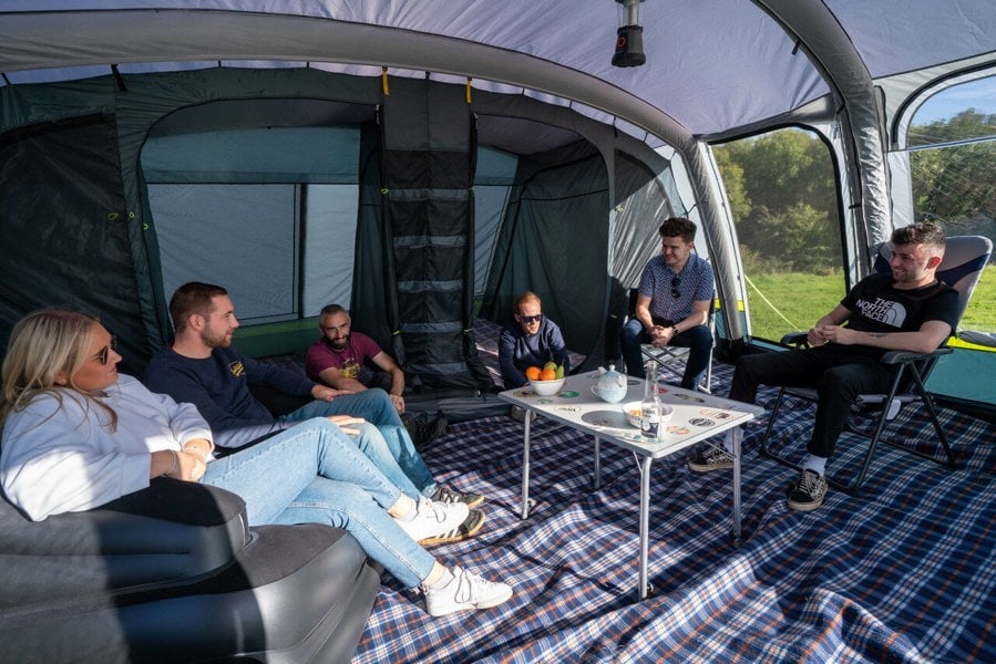 A group of young adults sat inside of the OLPRO Odyssey  Breeze® Inflatable 8 Berth Tent.