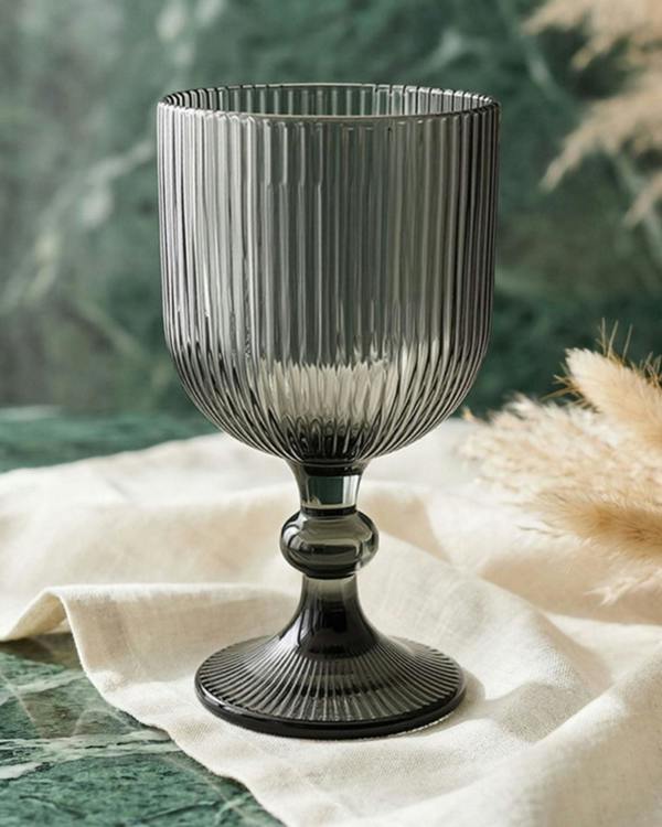 Set of ribbed glass goblets on a wooden surface with decorative elements.