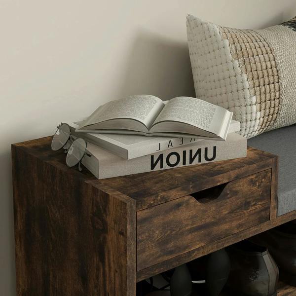 Rustic brown shoe bench with gray cushion and front drawer holding small accessories