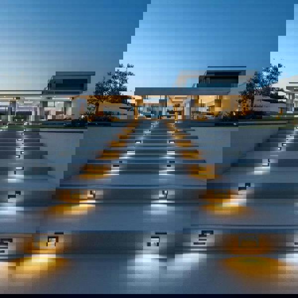 black low level external wall light mounted on concrete stair risers outside a modern home 