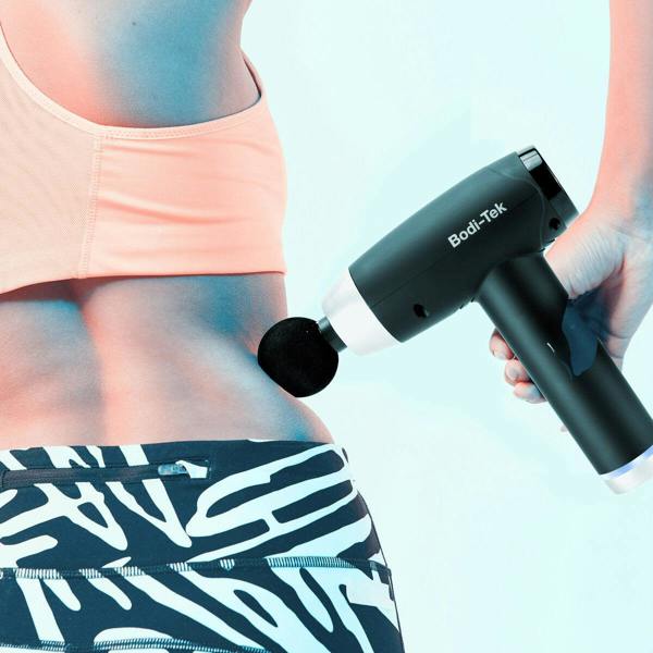 Wearing athletic wear, a person uses the Deep Tissue Sports Massage Gun on their lower back, holding it in their right hand against a light blue background.