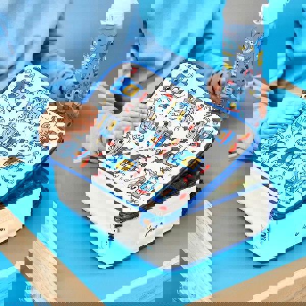 A lunchbox with blue robot designs is being opened by a child in a blue sweatshirt holding a matching bottle at a wooden table on a blue background. Text: ION8 Liam