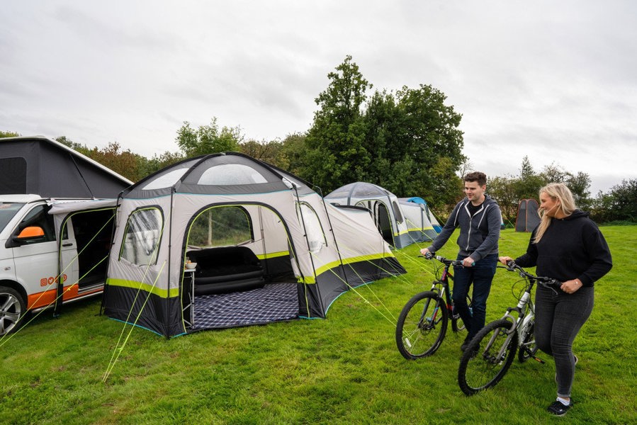 An adult couple walking with bicycles outside of the Hive Campervan Awning Fibreglass Poles - with Sleeping Pod from OLPRO.