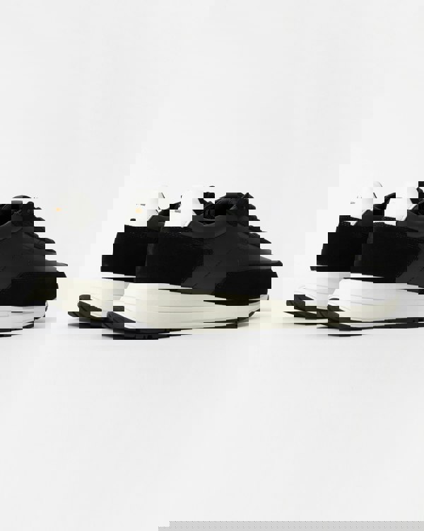 Black sneakers with white soles on a light gray background