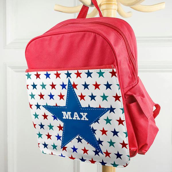 Personalised bright red kids mini rucksack hanging on a wooden peg rack, custom printed with the name MAX inside a large blue star.