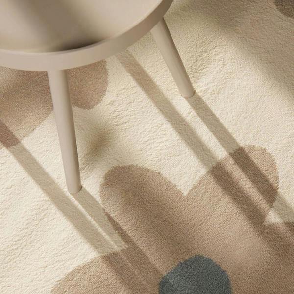 Beige carpet with abstract patterns and a white chair leg casting a shadow.