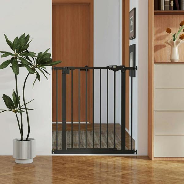 Black safety gate with vertical bars mounted across a doorway opening in home.