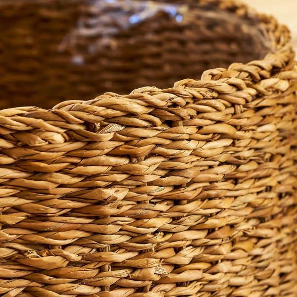 Close-up view of the top rim of the handwoven seagrass planter showing the clear plastic protective lining inside.