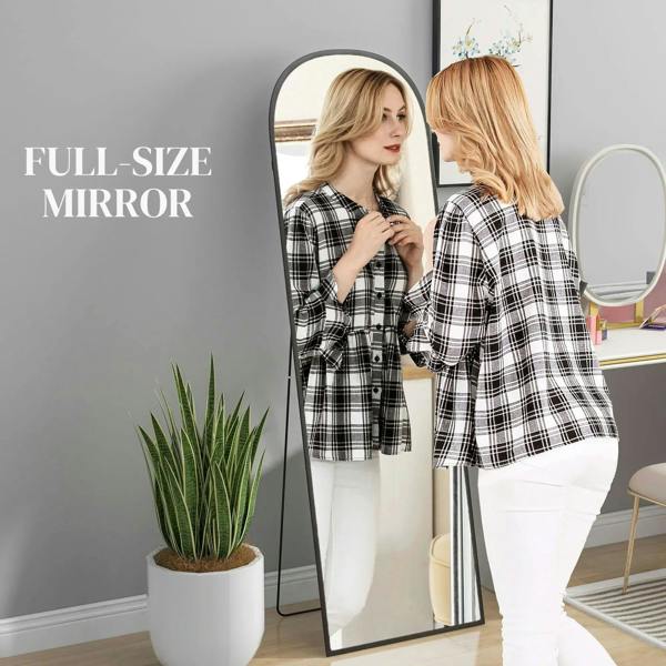 Black arched full-length mirror with slim metal frame standing upright