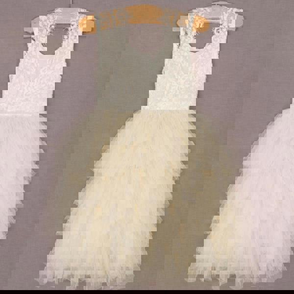 White lace dress with a ruffled skirt on a wooden hanger against a gray background