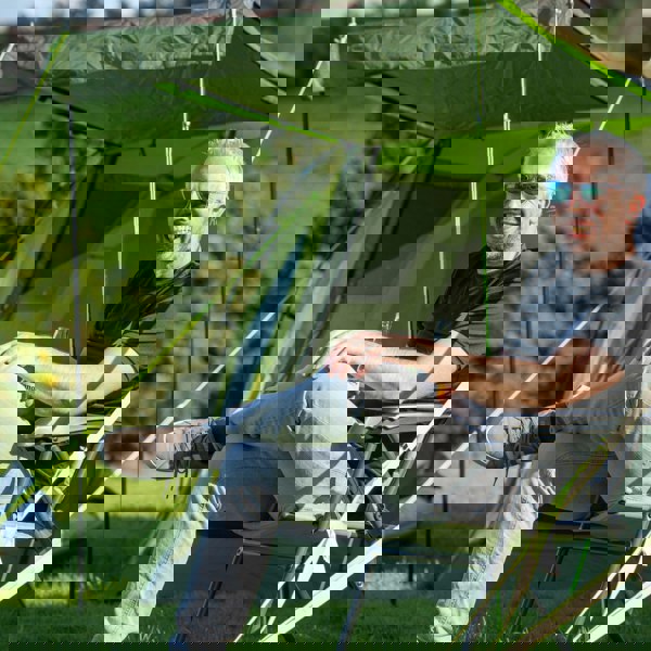 A male sat outside of the Abberley XL 4 Berth Tent by OLPRO at a campsite.