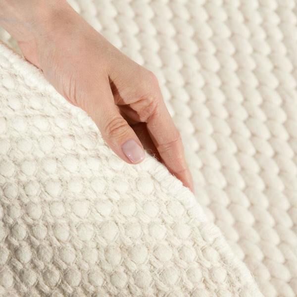 Hand touching a textured white fabric surface