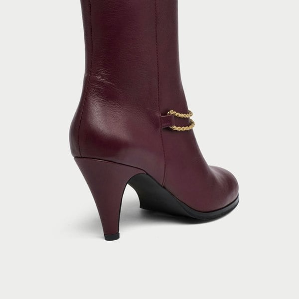 Maya cherry leather boot with gold chain detail on a white background heel close-up