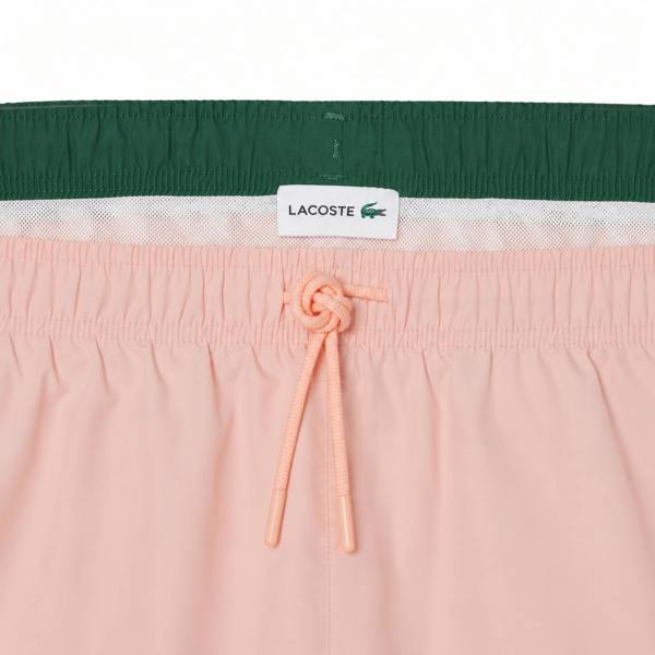 Lacoste pink quick-dry swim shorts with a green waistband and drawstring.