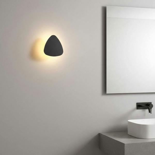 black bathroom sconce light mounted on the wall next to a bathroom mirror