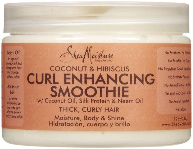 A jar of Shea Moisture Coconut Curl Enhancing Smoothie with the label detailing the addition of coconut oil, silk protein, and neem oil for moisture, body, and shine, specifically tailored for thick, curly hair.
