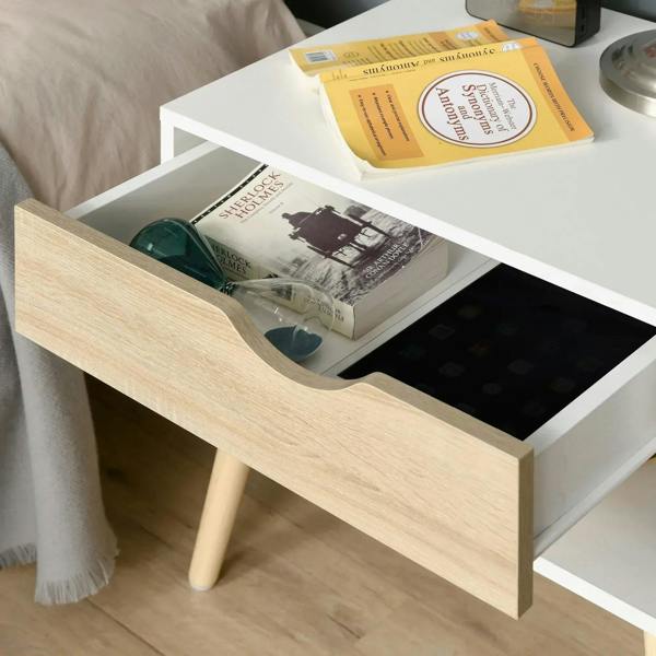 Close-up of light wood drawer front with cut-out handle on a white bedside table.