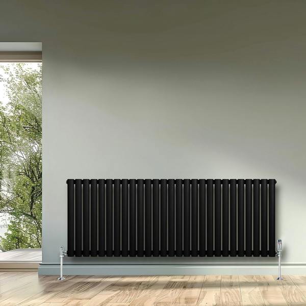 Sleek black oval single column radiator with chrome valves, mounted on a light grey wall, enhancing modern interior decor