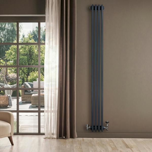 Traditional anthracite grey 4 column radiator with valves, standing against a wall near a large window with natural light