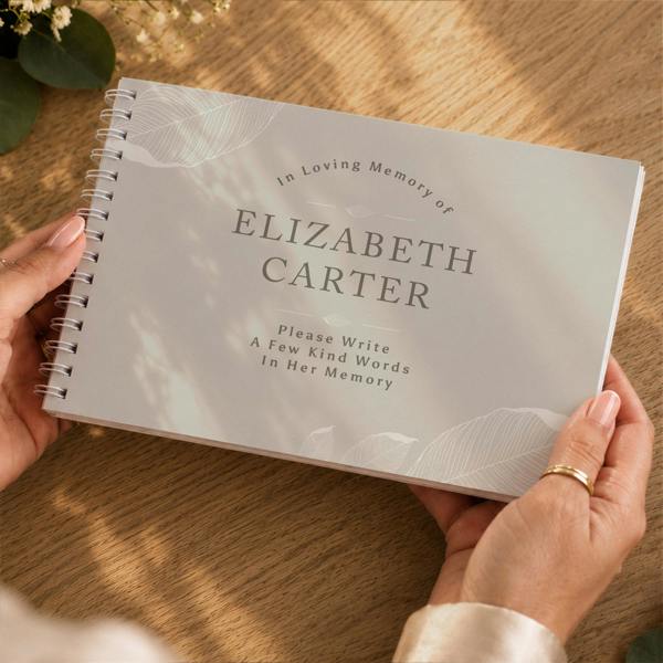 Hands holding the Personalised Memorial Guest Book showing custom name Elizabeth Carter on the cover by Abode Home & Gifts