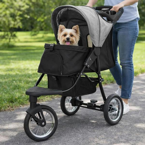 Grey pet jogger with a cozy canopy, featuring a happy small dog inside, rolling on a path surrounded by greenery