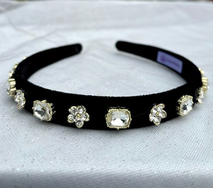 Black velvet headband, slim padded band, embellished with clear crystal gemstones, alternating square cut and floral cluster settings, gold tone accents, elegant statement hair accessory
