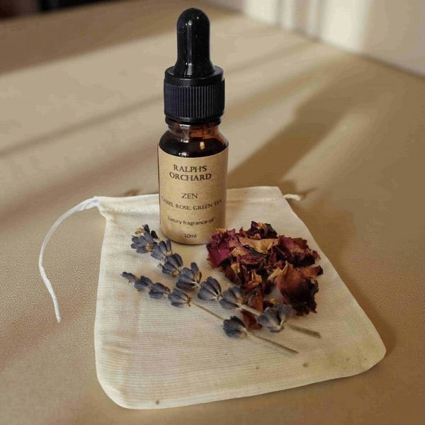 Bottle of Ralph's Orchard Zen essential oil with dried flowers on a beige cloth