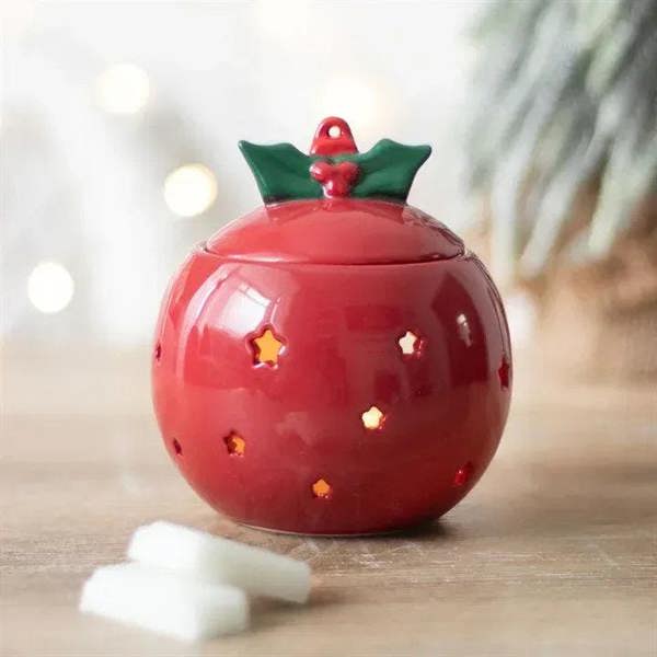 Red bauble oil burner with green holly cap, star cutouts, glossy finish.