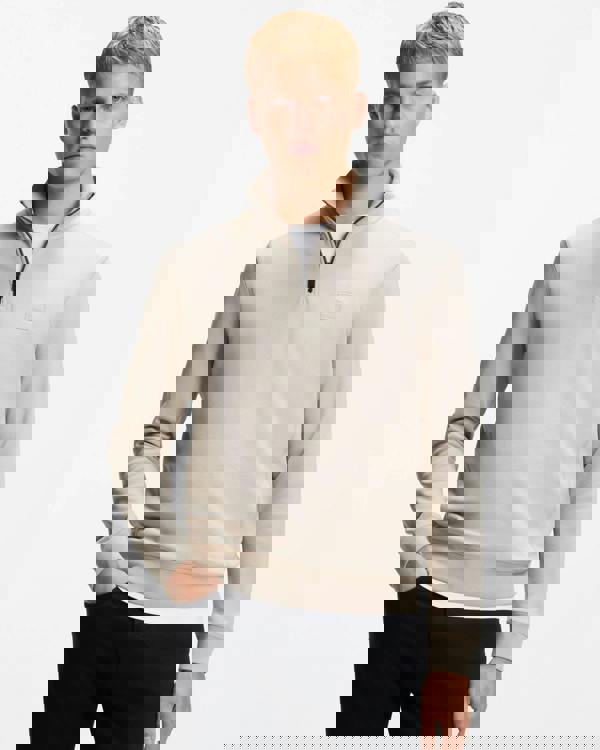 Man wearing a beige half-zip sweatshirt on a white background