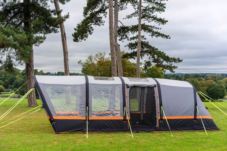 An image of the OLPRO Blakedown Breeze 4 Berth Inflatable Tent pitched on a campsite with a treeline in the background.