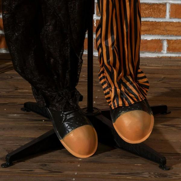 Circus clown animatronic legs and shoes on base, black-and-orange striped pants