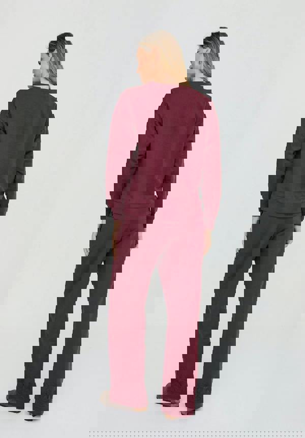 Woman wearing a burgundy sweatshirt and pants on a white background