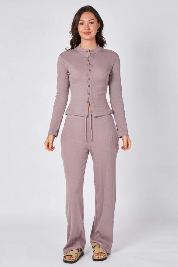 Woman wearing a mauve cardigan and pants set on a white background