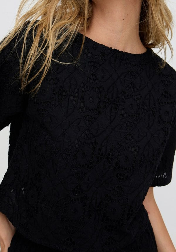 Black textured top worn by a person with blonde hair.