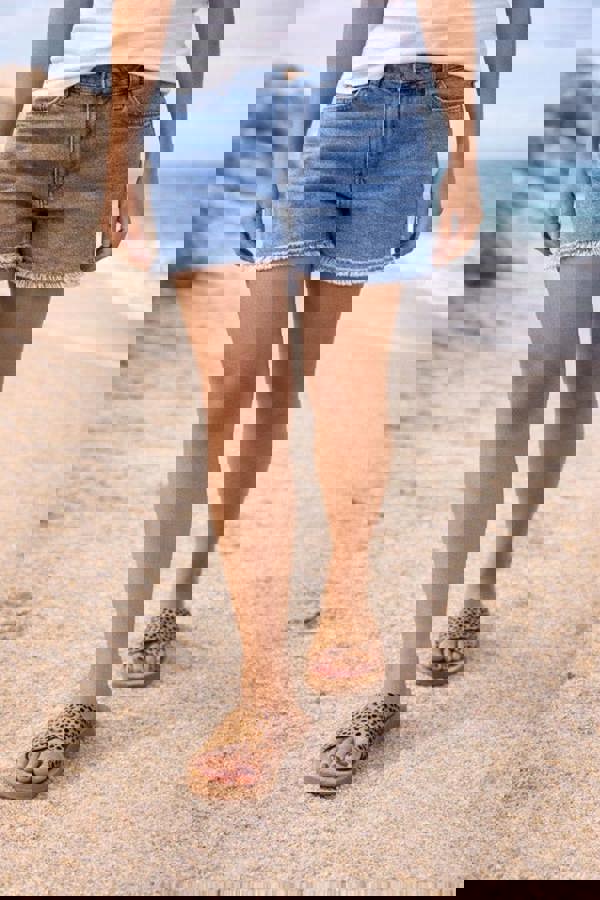 Person wearing denim shorts and sandals on a beach