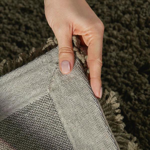 Hand touching a textured gray fabric against a brown carpeted background