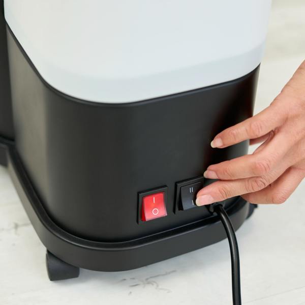 A hand presses the black power switch beside a red switch on the Fridja f1600 Commercial Clothes Steamer, with its power cord plugged in—perfect for efficient garment care.
