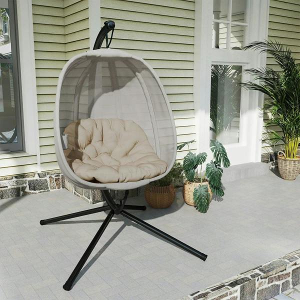 Hanging egg chair with khaki mesh pod and beige cushion on black tripod stand